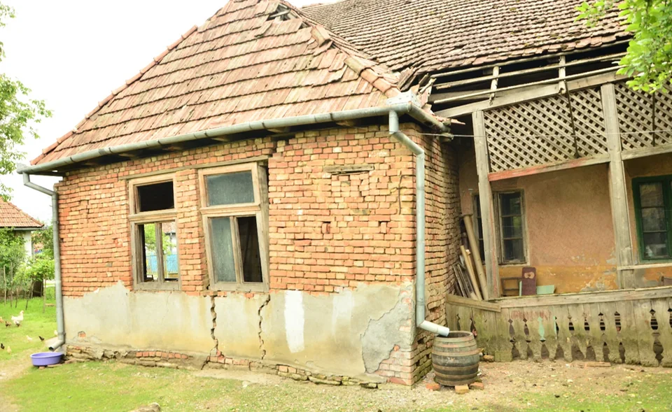 The family house in Suplac, with a brick front room and a wooden porch.