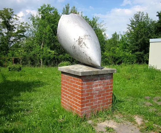 A metal bomb nose cone mounted on a brick pedestal.
