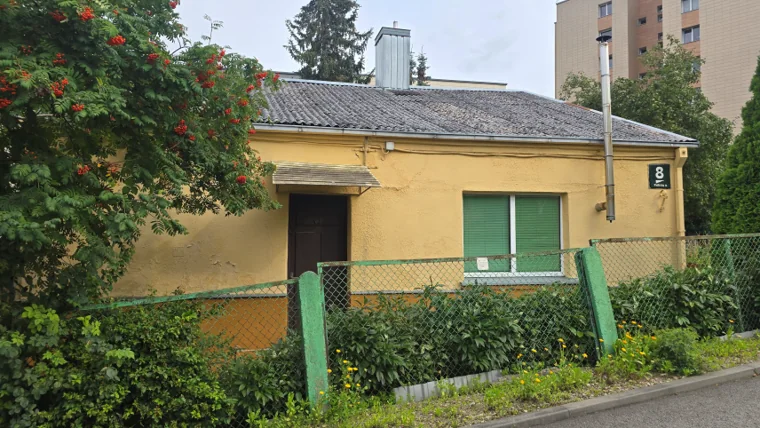 A single-storey yellow building with green shutters and a green fence, marked with the number 8.