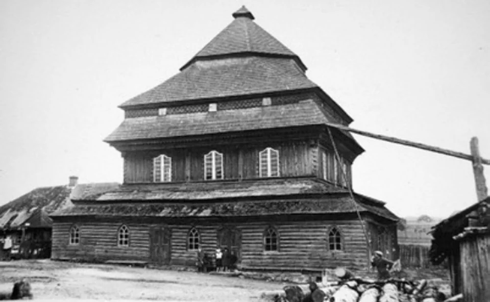 Black-and-white photograph of the wooden synagogue in Shukyan, with its tall, tiered roof.