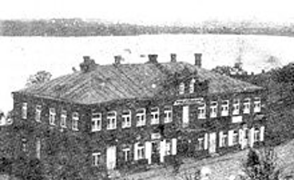 A historic photograph of a two-storey building near a body of water.